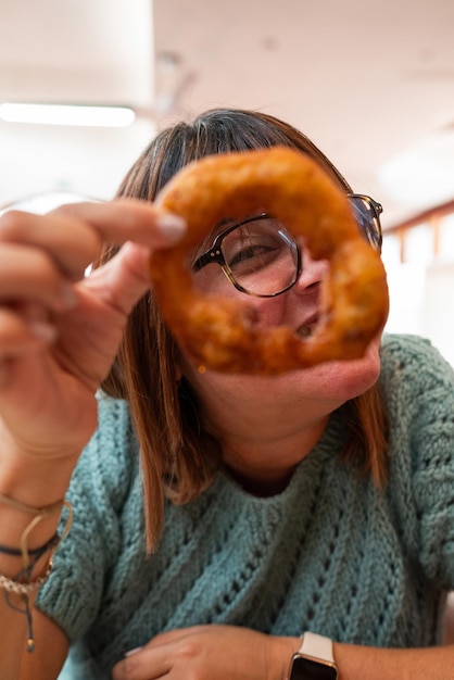 Woman looks playfully through a picaron with one eye Creative and funny food concept