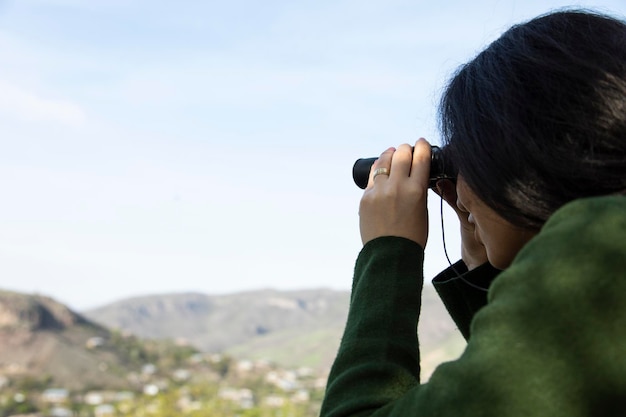 Photo woman looks through the binoculars in mountain