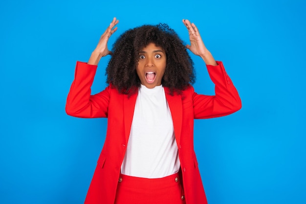 Woman looks with excitement at camera keeps hands raised over head notices something