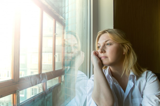 The woman lost in thought looking out the window. 