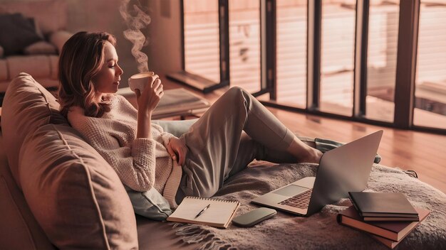 Photo woman lounging with coffee and laptop