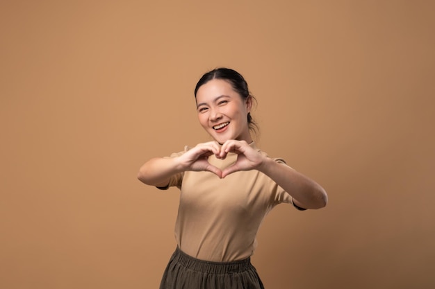 Woman in love making love symbol isolated on beige background