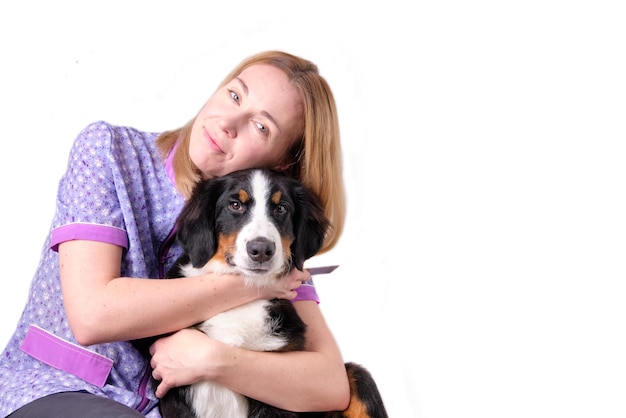 A woman lovingly embraces a Bernese mountain dog puppy 5 months isolated on a white background