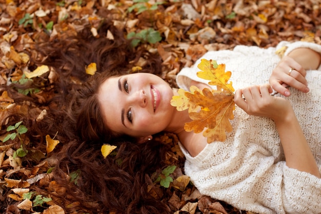 Woman lying on autumn leaves, outdoor portrait