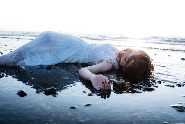 Foto donna sdraiata sulla spiaggia contro il cielo