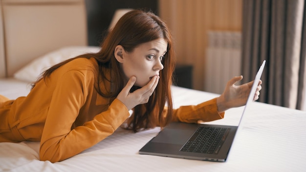 Woman lying on bed in front of laptop rest internet communication