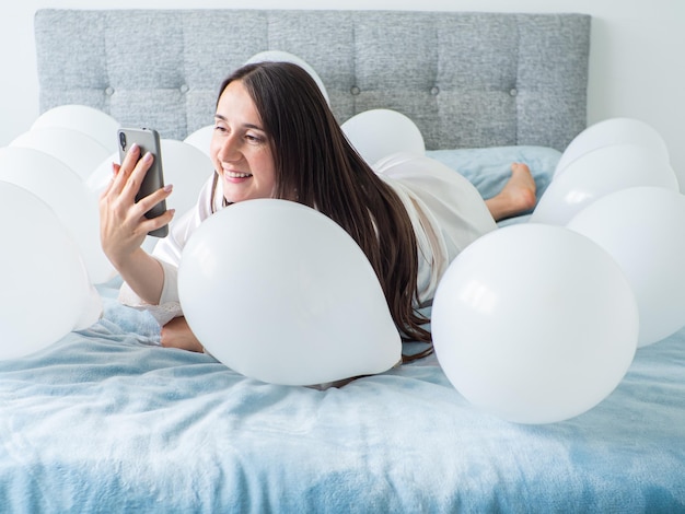 Woman lying on bed with decorations with balloons for Birthday party