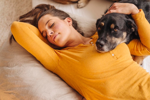 犬と一緒にベッドに横たわっている女性