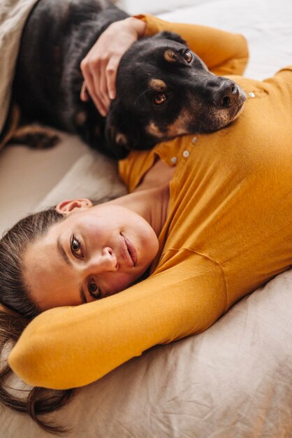 犬と一緒にベッドに横たわっている女性