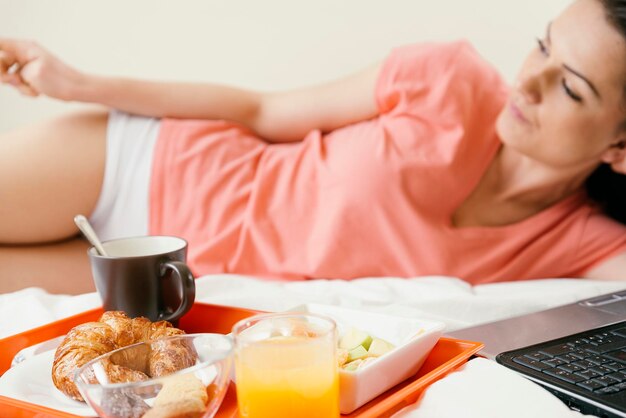 Photo woman lying by breakfast on bed