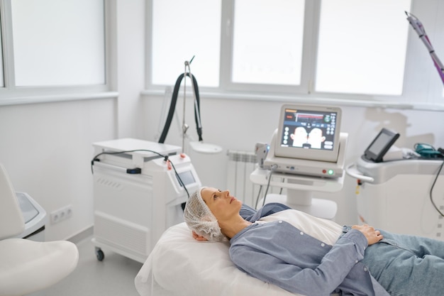 Woman lying on couch waiting for procedure at cosmetologist office