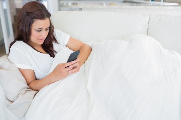 Photo woman lying on the couch while texting