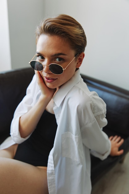 A woman lying on the couch with her glasses on and wriggling