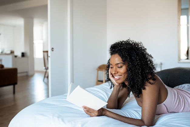 Woman lying down on bed reading a book