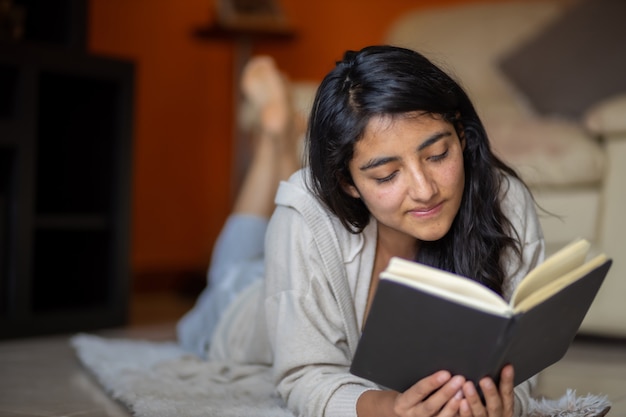 Woman  lying down looking at the side with a book at home