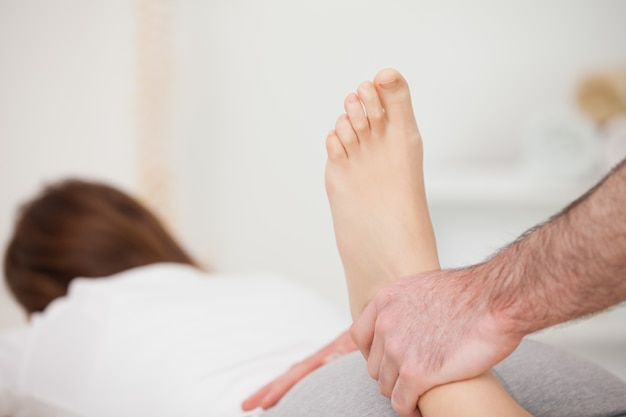 Woman lying forward while a physio manipulates her foot