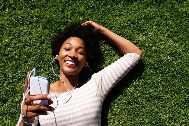 音楽を聴く草の上に横たわっている女性