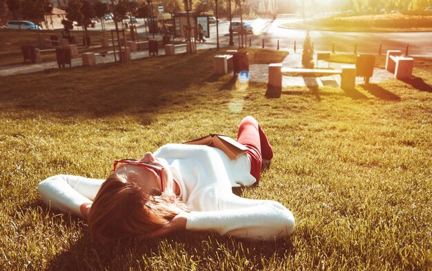 Foto donna sdraiata sul campo erboso in una giornata di sole