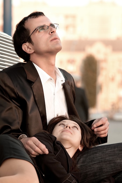 Woman lying on legs of man which sitting on bench