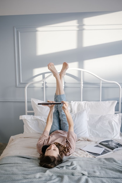 Фото Женщина, лежа на кровати с планшетом