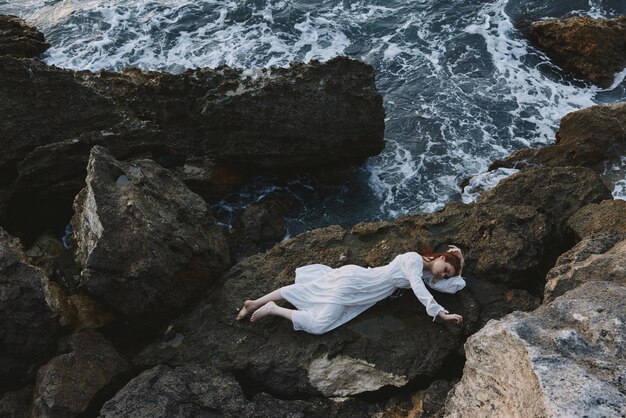 Woman lying on rocky coast with cracks on rocky surface nature\
landscape