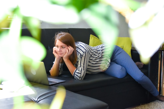 woman lying on a sofa in the home garden with a laptop working