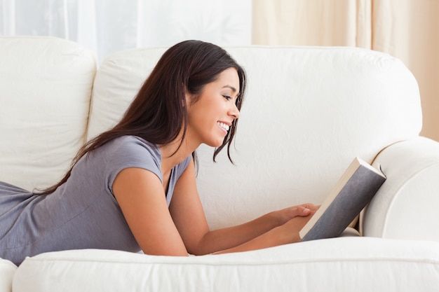 Woman lying on sofa reading a book