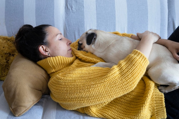 그녀의 퍼그 품종 강아지와 함께 휴식하는 소파에 누워있는 여자 애완 동물과 함께 휴식
