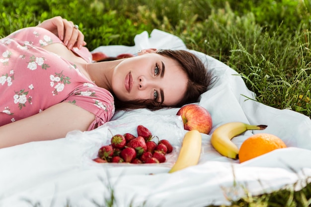 Woman lying on white bedsheet, looking at the camera, smiling