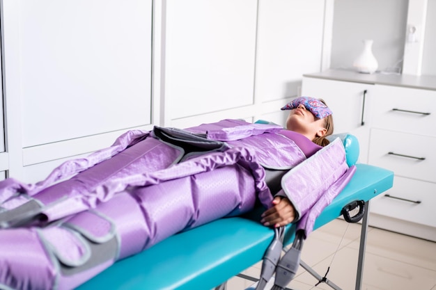 Photo woman lying with closed eyes during pressotherapy session in beauty clinic concept