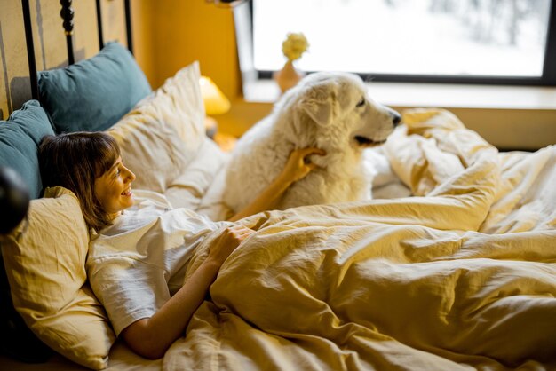Photo woman lying with her huge and cute dog in bed