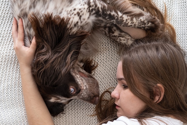 Woman lying with Russian spaniel dog chocolate merle different colours eyes. on couch. Pets care concept.