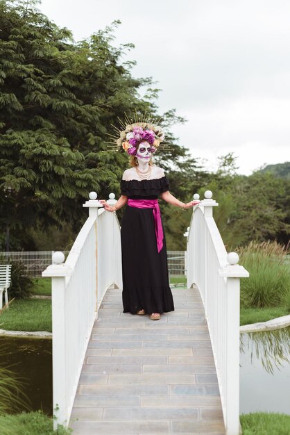 Woman made up as catrina. Mexican woman celebrating day of the dead. Outdoor portrait with Halloween makeup.