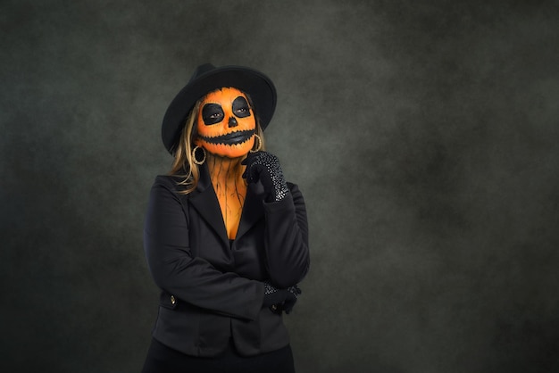 Woman made up as a pumpkin to celebrate Halloween in a pensive attitude.