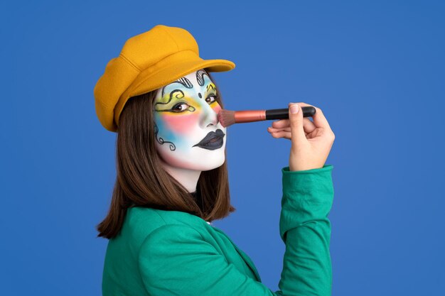 Woman made up for carnival on blue background with makeup brush