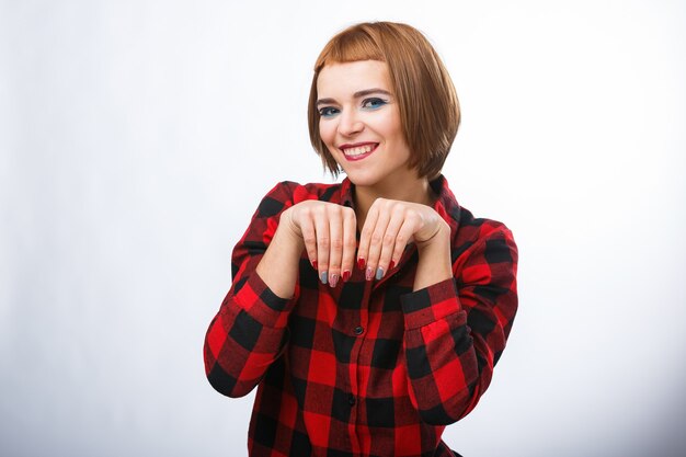 Woman makes bagging sign with hands. Young woman's portraits with different happy emotions. Checkered shirt and red hair. Pitiful emotions.