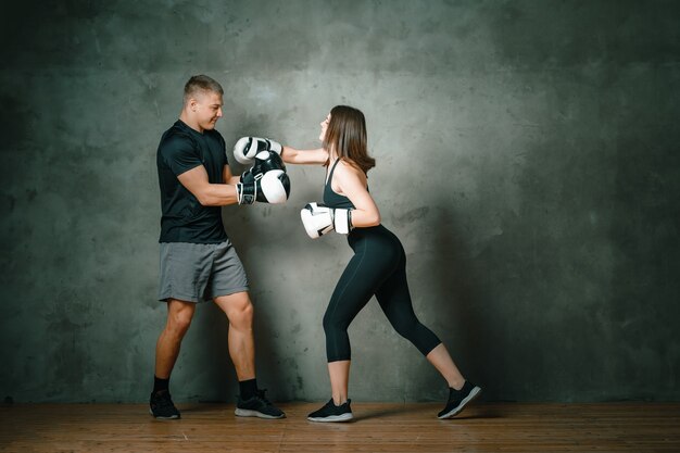 Photo a woman makes a blow to the head of a man on a dark gray background