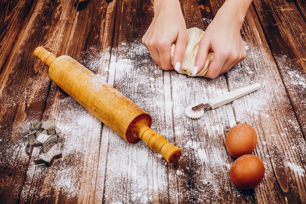 Woman makes Christmas pastry on the dough on wooden table 