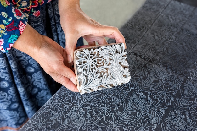 Photo a woman makes a drawing on a fabric using a hand stamp and paint