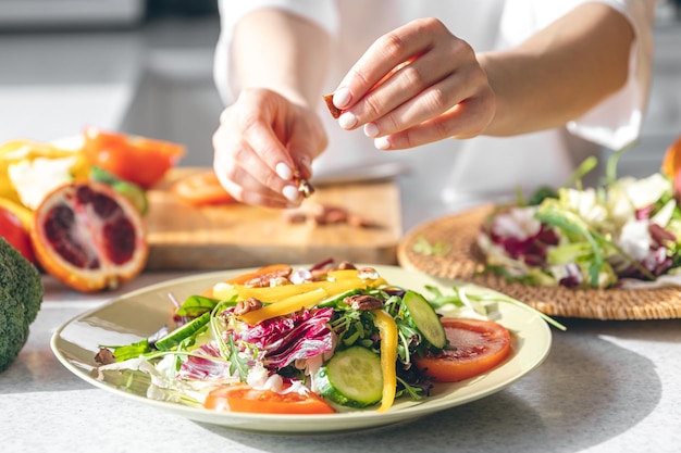 A woman makes a fresh vegetable salad closeup