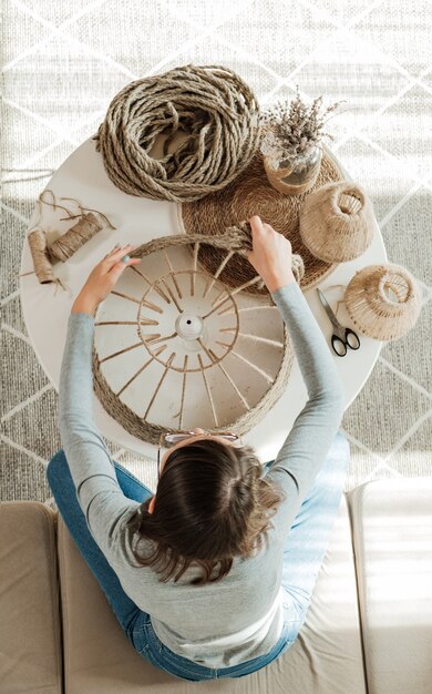 Woman makes handmade diy lamp from jute rope, top view