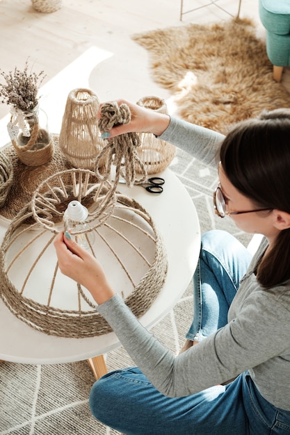 Woman makes handmade diy lamp from jute rope