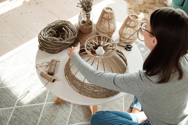 Woman makes handmade diy lamp from jute rope