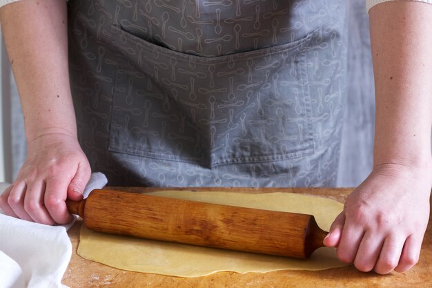 A woman makes homemade noodles from flour, eggs and salt. Rustic style.