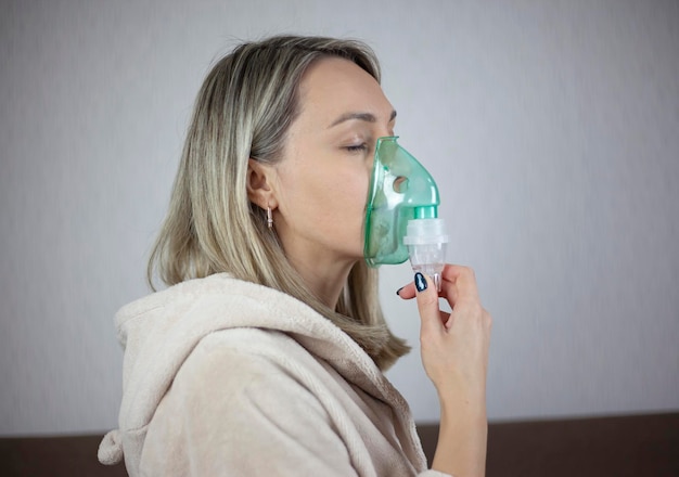 Foto donna fa un nebulizzatore per inalazione a casa con una maschera nebulizzatore per inalazione spray di fumi