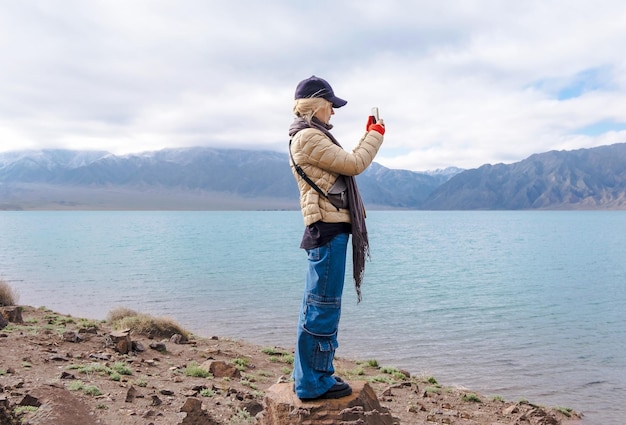 Woman makes landscape photo Travel scene girl takes a picture Bartogai reservoir Almaty Kazakhstan