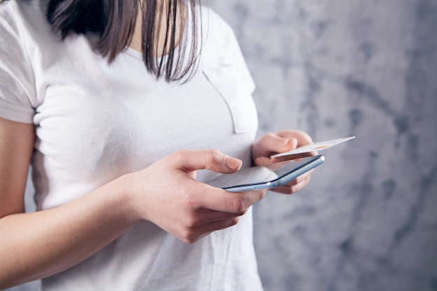 Woman makes a payment by phone through a card on a gray background