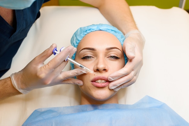 Woman makes rejuvenating facial injections procedure for lips augmentation