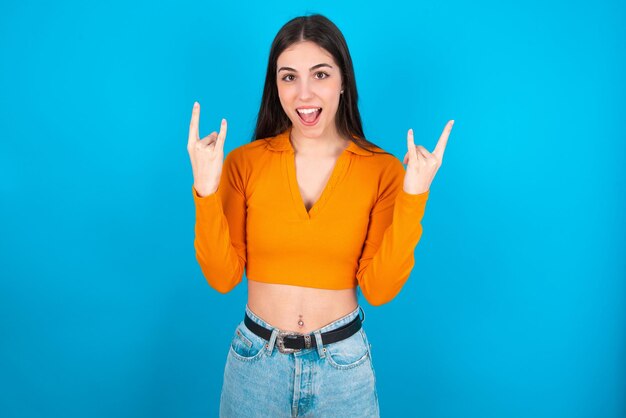 Woman makes rock n roll sign looks self confident and cheerful enjoys cool music at party