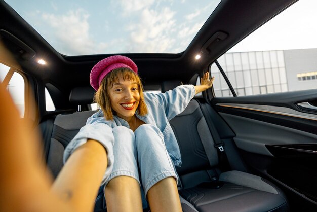 Woman makes a selfie while sitting on backseat of a car